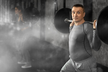 Athlete middle-aged man during exercises to strengthen muscles of back and body using barbell