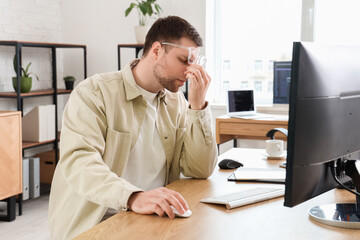 Portrait of tired male programmer working in office