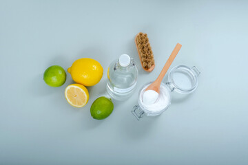 Natural household cleaning products baking soda, white vinegar, citrus fruit, brush on a gray...