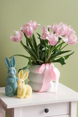 Vase with flowers and bunnies on table, closeup. Easter celebration