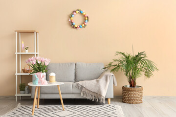 Interior of modern living room with flowers, bunnies and Easter cake on coffee table