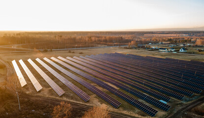 Fototapeta na wymiar Aerial view of industrial sized solar panel farm during sunset, illustrating the blend of technology and nature
