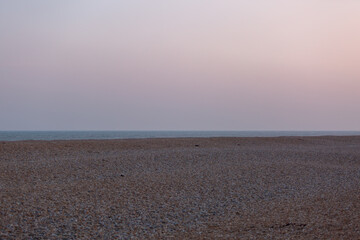 View of the English channel from a shingle beach, Image shows a cloudy evening on the English coast looking out to the North sea with various colours in the sky