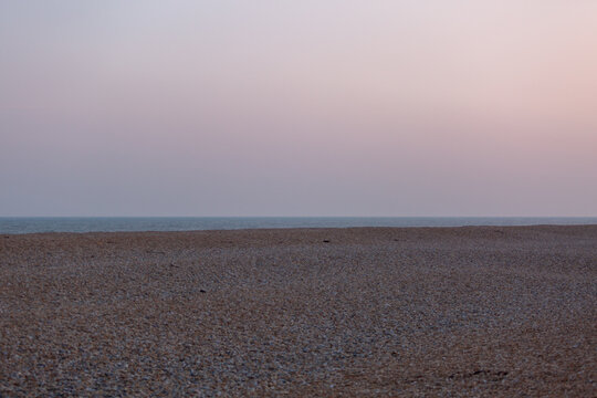 View of the English channel from a shingle beach, Image shows a cloudy evening on the English coast looking out to the North sea with various colours in the sky