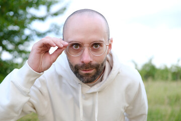 pretty bearded young man 30 years old in glasses looks intently through lenses, concept human...