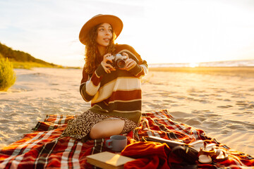 Young Woman at the Beach with Vintage Camera. Picnic, relax, weekend. - obrazy, fototapety, plakaty
