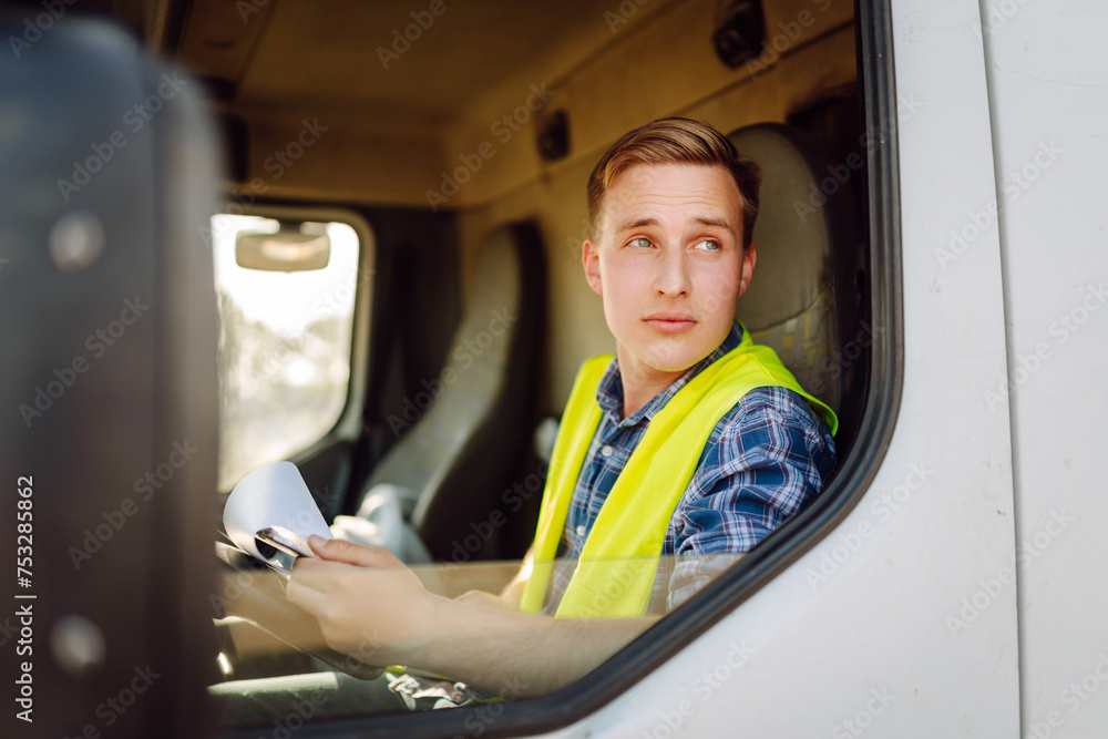 Wall mural Truck driver job. Logistics - proud driver or forwarder on truck and trailer, on a transshipment point. Transportation service.