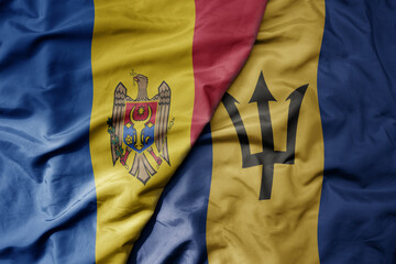 big waving national colorful flag of barbados and national flag of moldova .