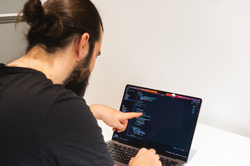 A programmer thinks about how to solve a complex problem. Professional software engineer, IT specialist, working from home and writing code on a laptop computer.