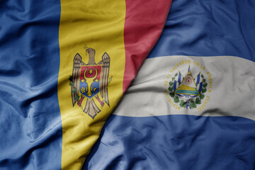 big waving national colorful flag of el salvador and national flag of moldova .