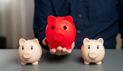 Red bloated piggy bank against the background of normal ones. Overheated financial market....