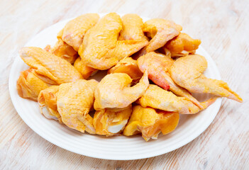 Close up of raw yellow chicken wings on wooden background