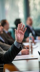 A person raising his hand during a seminar in a professional meeting room. Business person with hand raised in request for an answer to a question.
