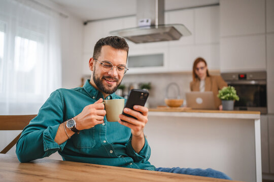 man with eyeglasses stand at home use mobile phone sms texting