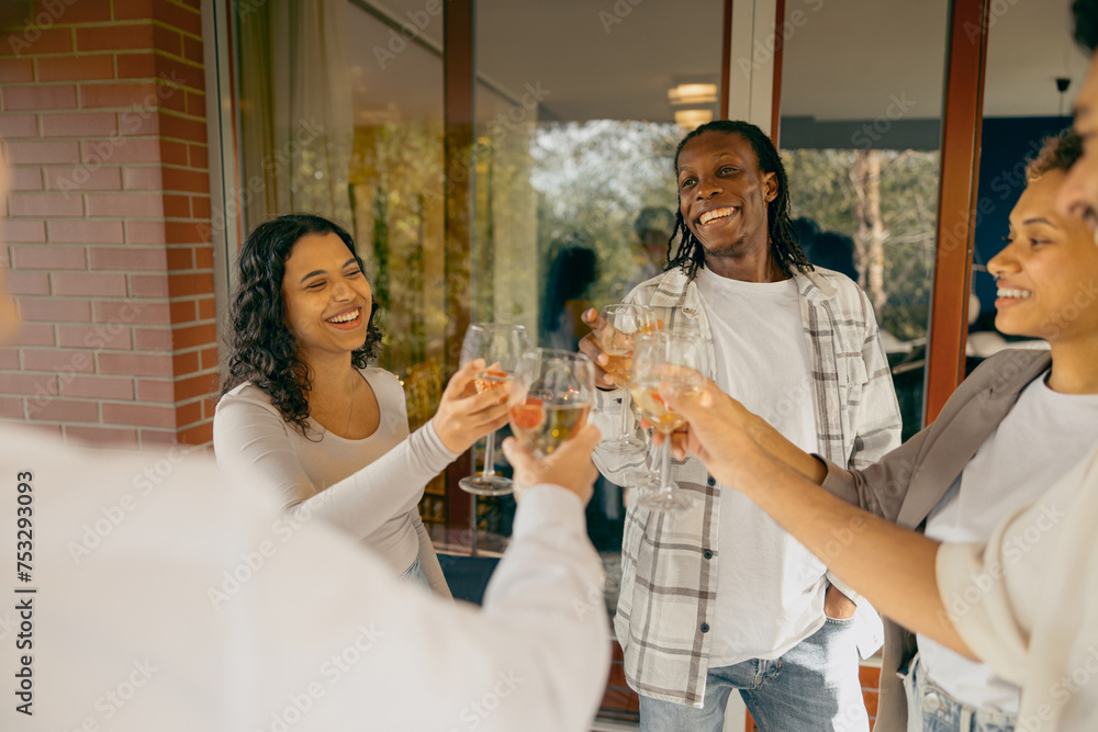 Wall mural Group of happy friends is drinking wine and clinking glasses having holiday dinner party at home