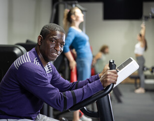 African american man doing cardio workout out, training on exercise bike