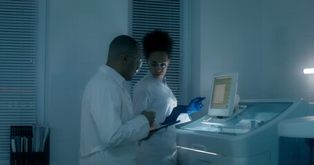 Work in a medical laboratory. A man and a woman in lab coats set up a blood splitting device using a tablet