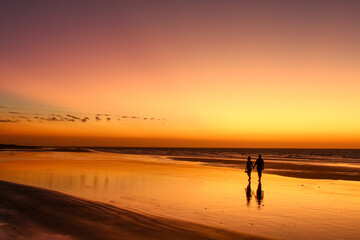 Silhouette couple on beach against sky during sunset - Powered by Adobe