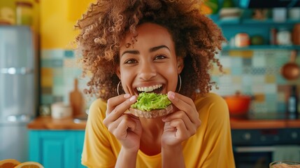 a woman happily eating smashed avocado on toast in a colourful kitchen - obrazy, fototapety, plakaty