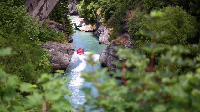 Speedboat jet boat in river in canyon. New Zealand extreme sport for thrill seekers, adventure travel, backpacking. 