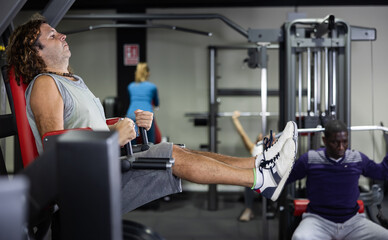 Fototapeta na wymiar European athlete pulls his legs to his chest on a special simulator