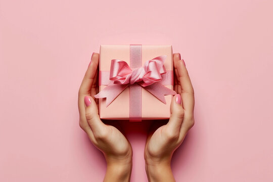 pink gift box with ribbon on pink background.