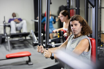 Fototapeta premium Caucasian man training on chest fly machine in gym
