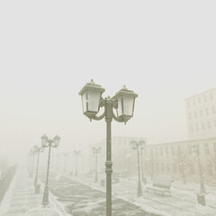 Snow-Covered Urban Park Lamps and Benches on a Misty Winter Dawn