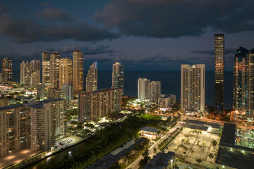 Fototapeta na wymiar Aerial view of downtown district in Sunny Isles Beach city in Florida, USA. Brightly illuminated high skyscraper buildings in modern american midtown