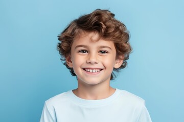 Portrait of a smiling little boy with curly hair on blue background - obrazy, fototapety, plakaty