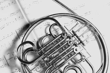 Elegant French Horn on Scattered Musical Scores in Monochrome Tone