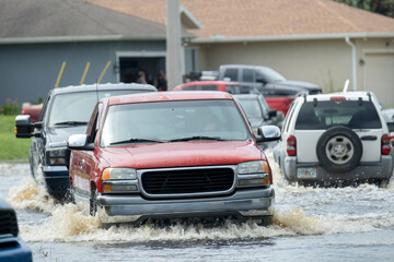 Flooded american street with moving vehicles surrounded with water in Florida residential area....
