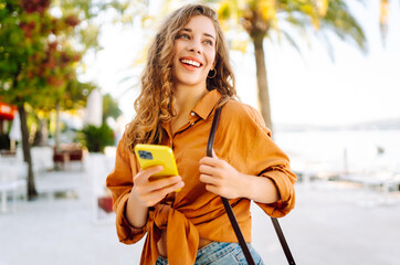 Young woman on vacation smiling happy. Standing with smile on face using smartphone at street of...
