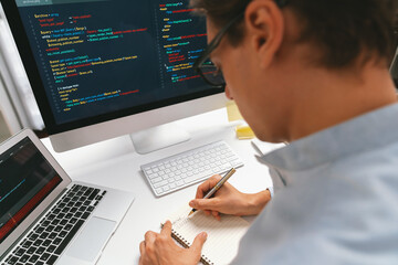 Stressful IT developer analyzing online software development information on pc and laptop with...