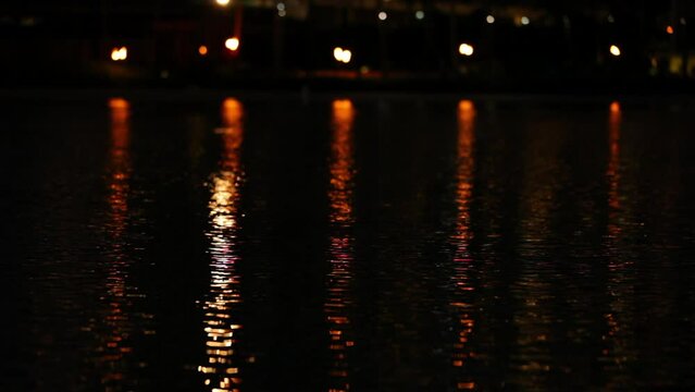 Orange lights reflecting in shimmering water - locked off shot