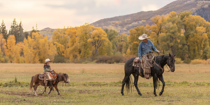 Father and son cowboys on horse and pony riding in the colorful mountains - Powered by Adobe