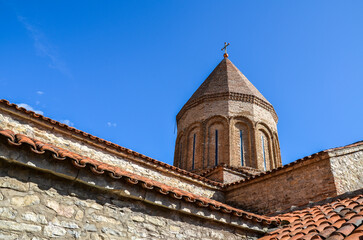 Fototapeta na wymiar Tiled roof of the cross-domed church of the Saviour built of river stone and brick at the Ananuri Fortress complex in Georgia