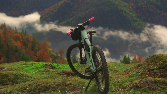 Electric bike stands on high mountain above clouds in autumn in Bavarian Alps. Brightly colored mountain e bike against German alps in higher than clouds. Theme travels in alpine by eletro cycle. 