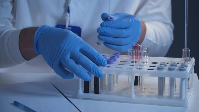 Health care worker with blood test tubes in clinical laboratory. Medical examiners hand holding blood sample for analysis in clinical research laboratory. Disease prevention starting in science center