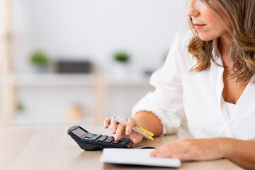 Close-up cropped photo of a mature woman preparing home budget using calculator
