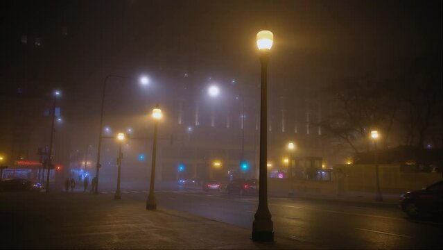 Cars drive on empty road of fog at night time. Chicago street. 