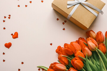 Gift box with a bow and a bouquet of red tulips, top view, background