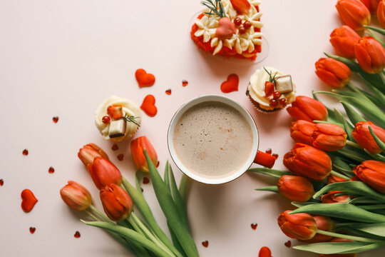 Cup of coffee, bouquet of red tulips and cake top view flat lay, festive background