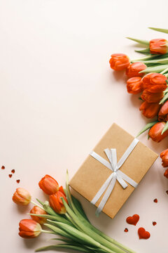Gift box with a bow and a bouquet of red tulips, top view, background