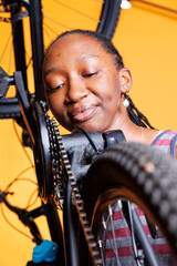Detailed view of black woman carefully examining bicycle chain stay for optimal cycling. Young lady in up-close shot, showcases her attention to detail as she diligently maintains her bike components.