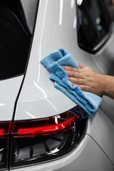 Papier Peint photo Poney A mechanic wipes the body of a white car with a microfiber cloth. 
