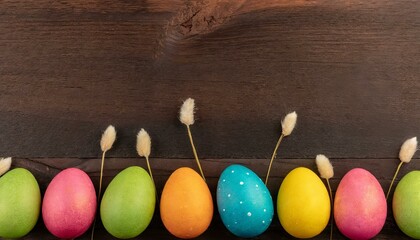 Obraz premium Colorful Easter Egg bottom border over a dark wood banner background. Copy space.