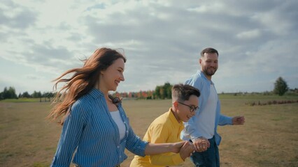 Happy European family smiling laughing man woman couple little boy son kid running outside nature countryside meadow mom dad child holding hand run rural field happiness joy parenting custody adoption