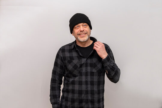 A 50-55 year old man in a plaid shirt pulls back the collar on a white background.