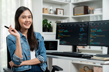 Young Asian in IT developer looking at camera to present with online information on pc with coding...